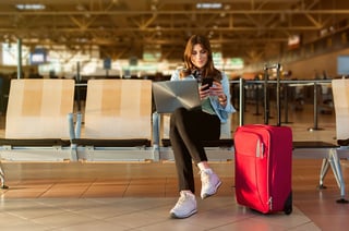 Airport Young Female Passenger On Smart Phone And Laptop Sitting In Terminal Hall While Waiting