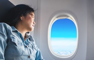 Asian Woman Sitting At Window Seat In Airplane And Look Outside Window See Blue Sky