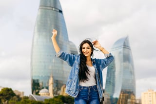 attractive young brunette girl laughing posing against a background of modern buildings in the