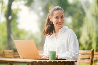 Jeune femme attirante profitant de travailler en plein air sur la terrasse d’un café dans un parc